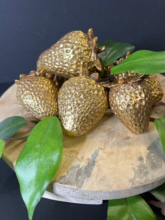 Gold decorative strawberries with green leaves on a dark background