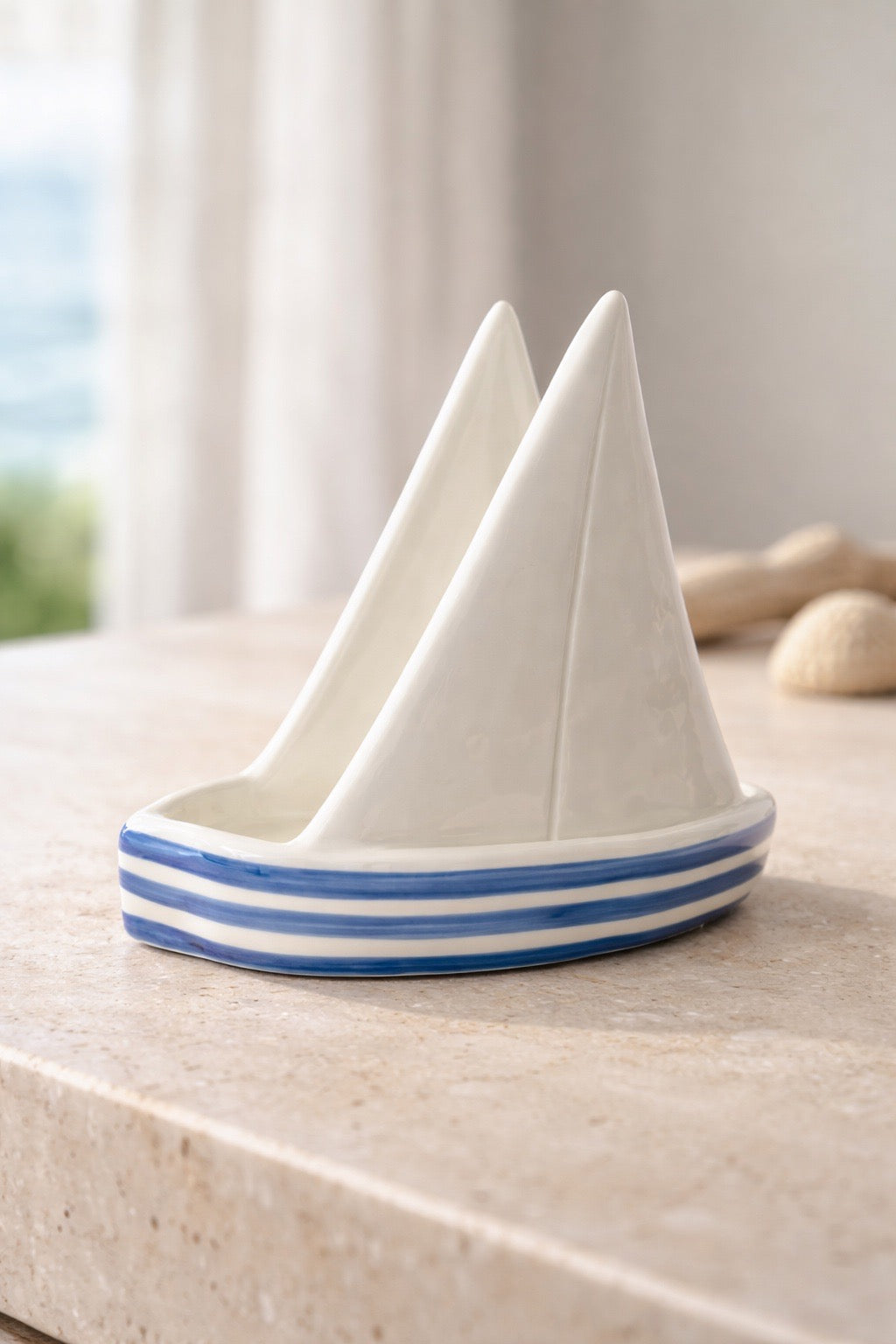 Ceramic sailboat with blue stripes on a light surface