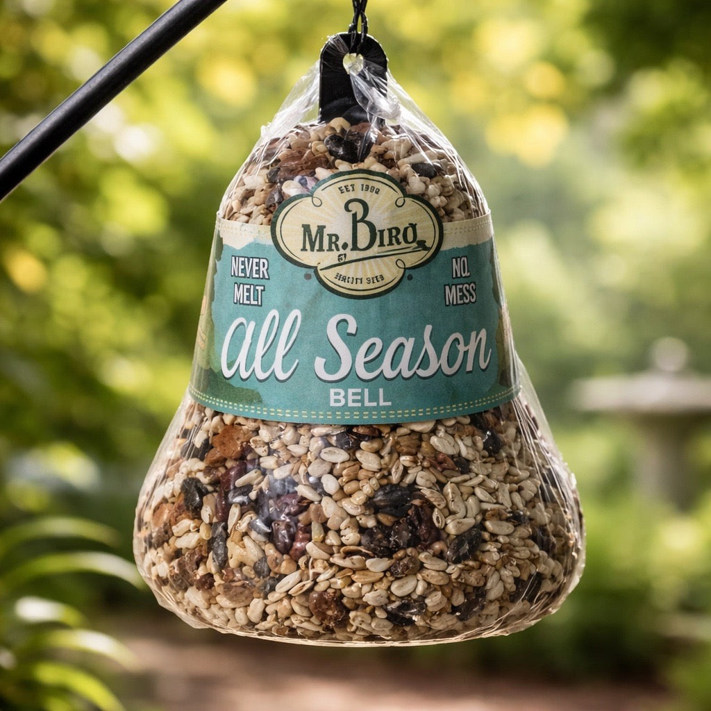 Bag of birdseed labeled 'Mr. Bird' hanging outdoors with a blurred green background