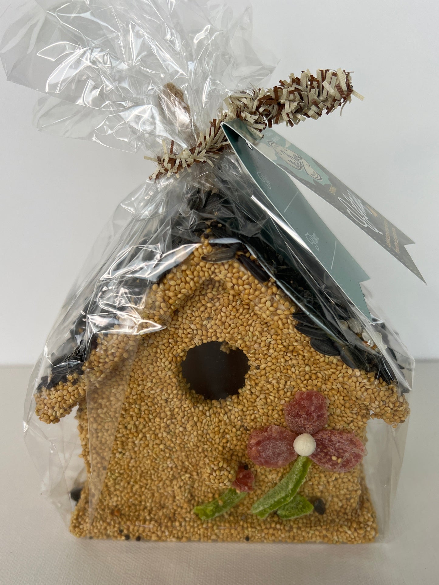 Birdseed-filled birdhouse with decorative elements on a white background